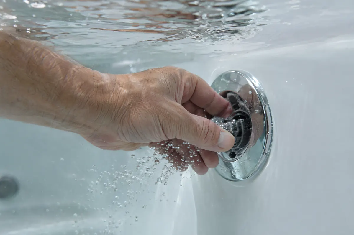 Illustration: a hand turning a chrome whirlpool jet under water