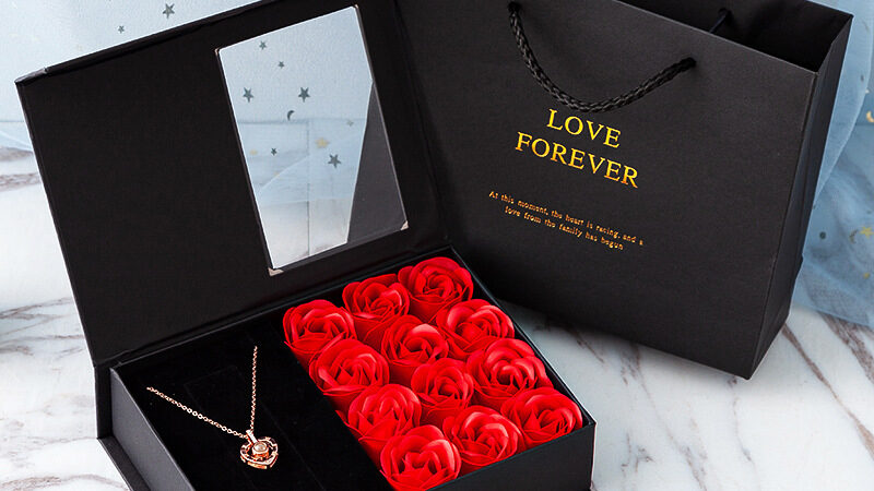Romantic gift box with red roses and necklace, prepared as a surprise for a hotel room celebration