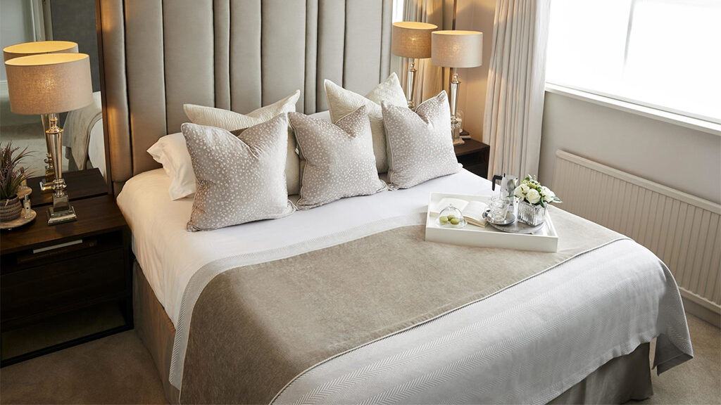 Luxury hotel bed with decorative pillows and a breakfast tray, styled for a romantic stay