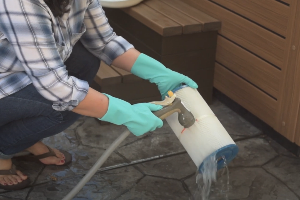 Cleaning a filter Cleaning a hot tub filter with water to remove debris and buildup