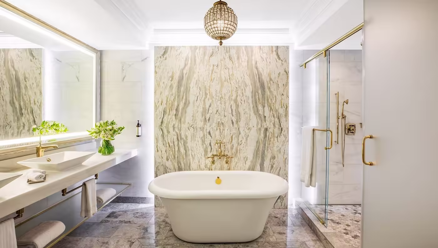 Claremont Resort & Club Luxury hotel bathroom with a deep soaking tub, marble walls, double vanity, and glass shower enclosure