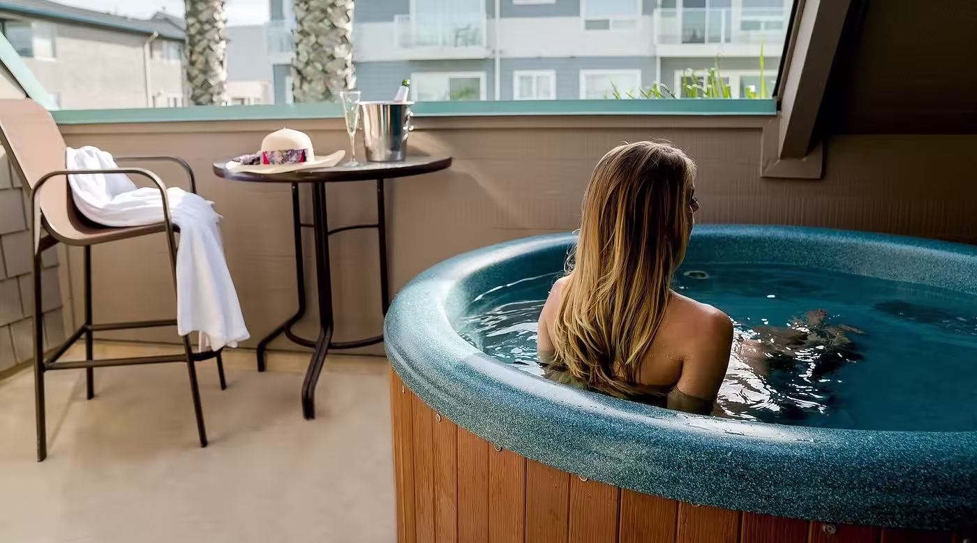 SeaVenture Beach Hotel Person sitting in a hot tub on a private balcony with table, drinks, and nearby buildings visible
